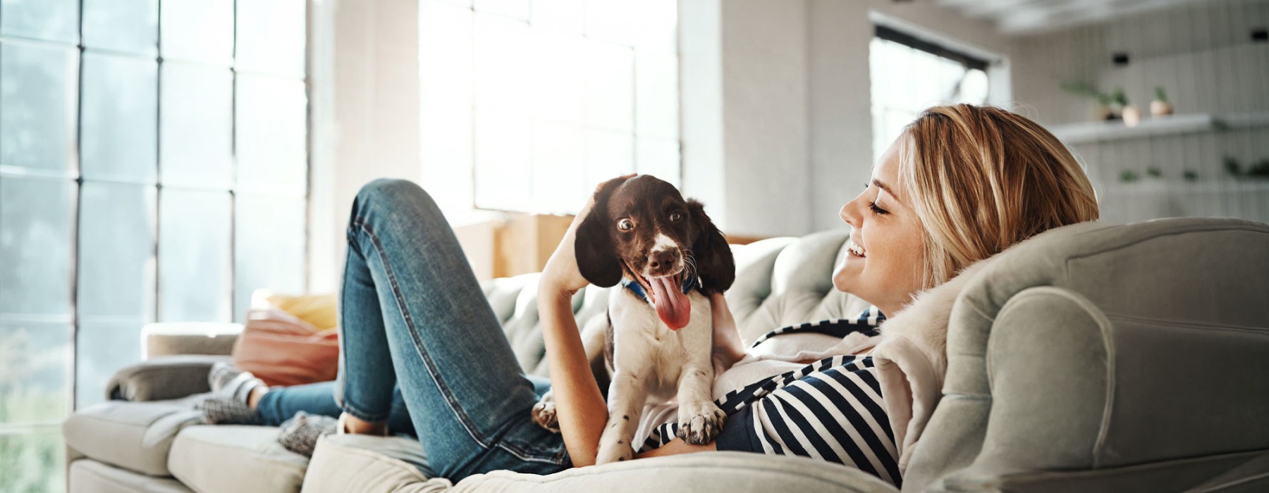 woman lies on a couch and pets her dog